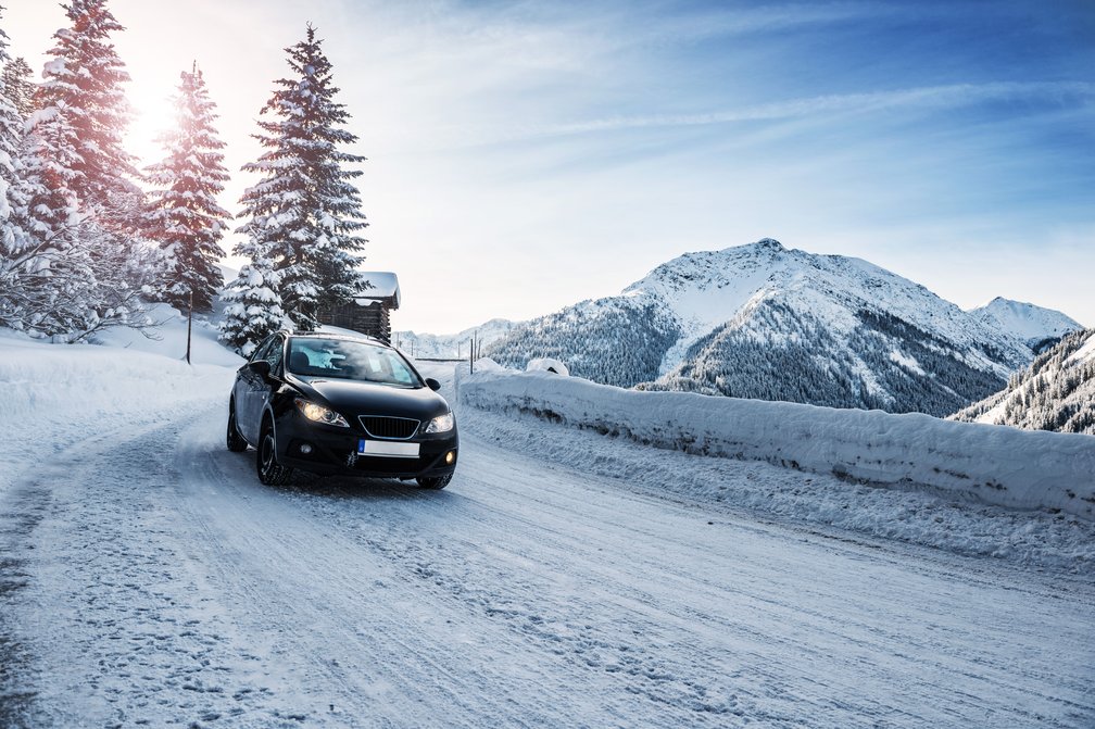 Schwarzes Auto fährt verschneiten Bergpfad hinunter