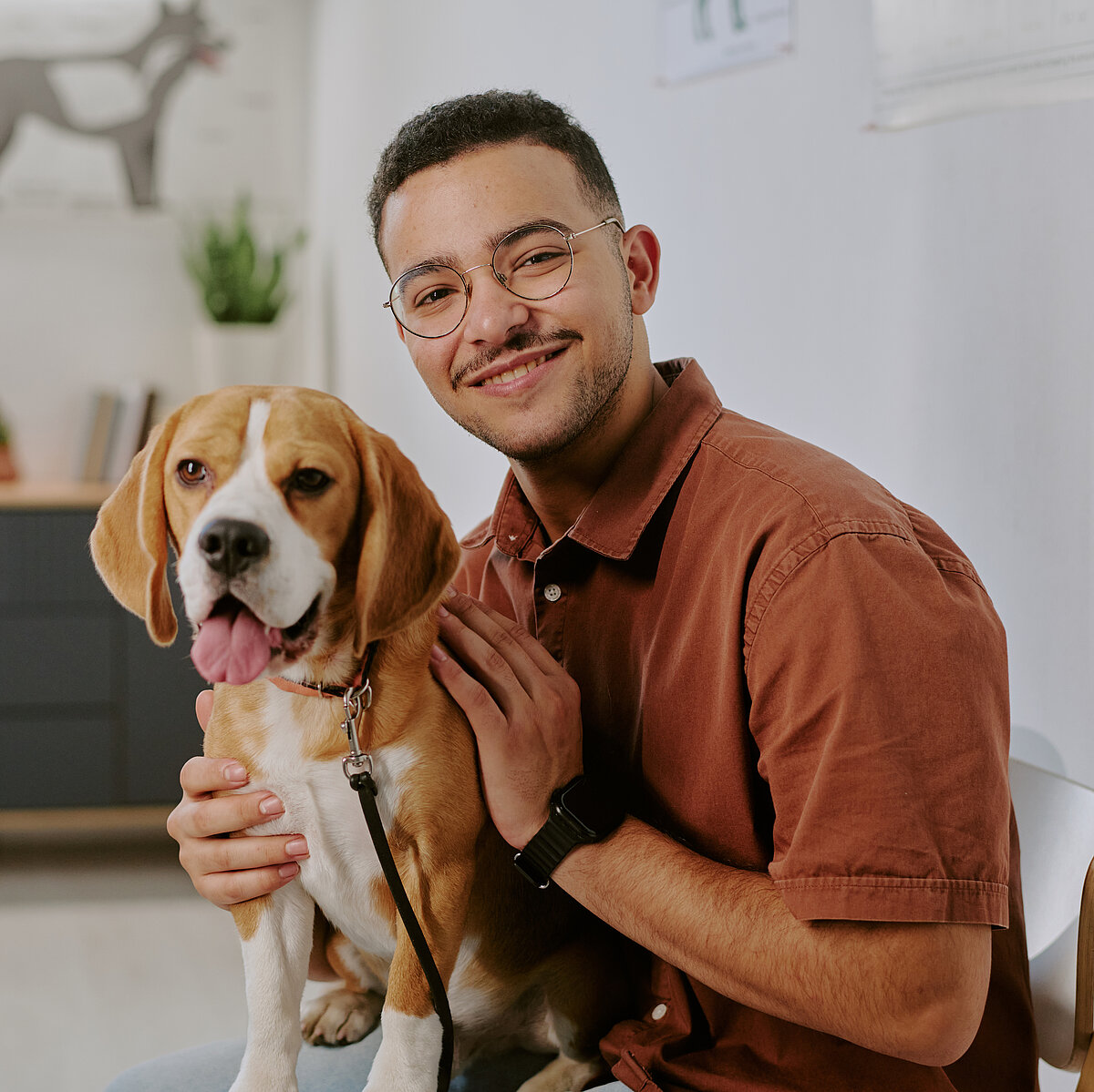 Porträt eines lächelnden Mannes, der in der Tierarztpraxis sitzt und einen Hund hält
