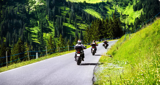 Motorradfahrer fahren im Sommer an Bergen vorbei