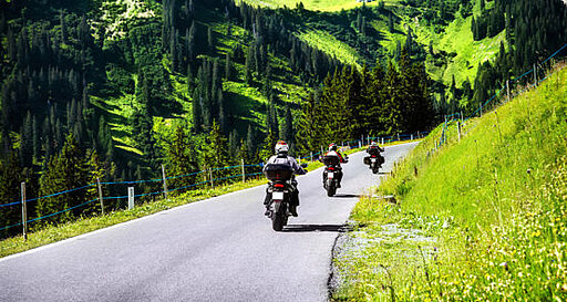 Motorradfahrer fahren im Sommer an Bergen vorbei