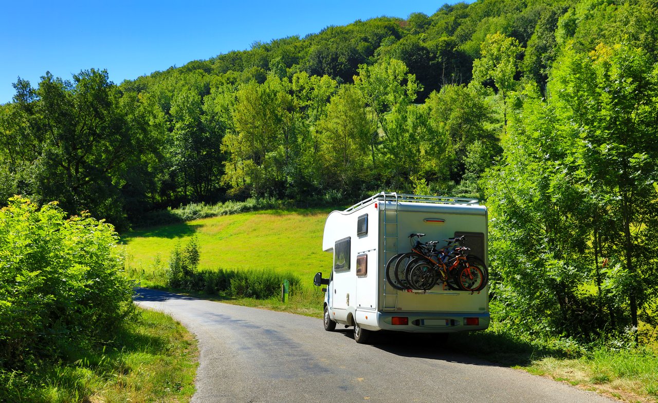 Wohnmobil fährt auf einer kleinen Straße durch eine grün bewachsene Landschaft