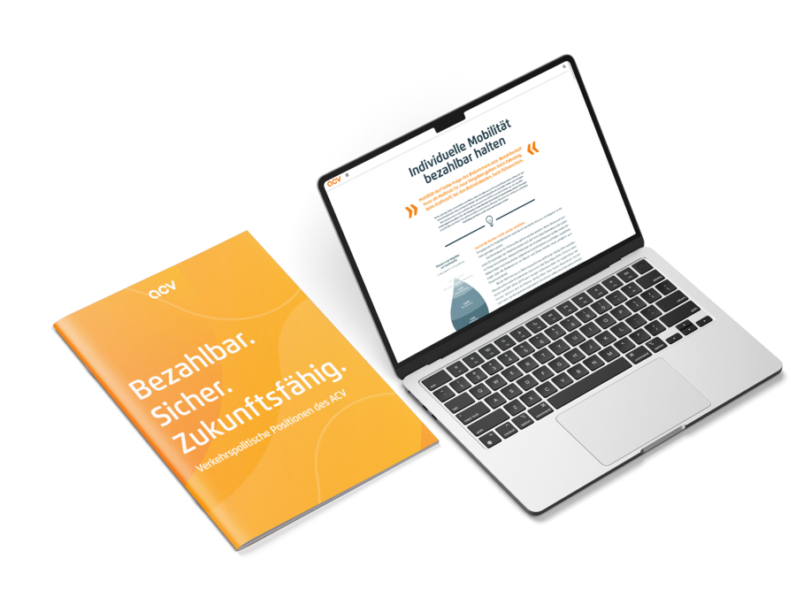 Neben einem geöffneten Laptop, auf dessen Bildschirm eine Website zu sehen ist, liegt eine orangefarbene Broschüre mit deutschem Text – beide auf einer weißen Unterlage. Auf der Broschüre steht: „Bezahlbar. Sicher. Zukunftsfähig. Verkehrspolitik – Positionen des ACV“.