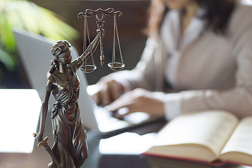 Eine Figur der Justizia steht auf einem Tisch