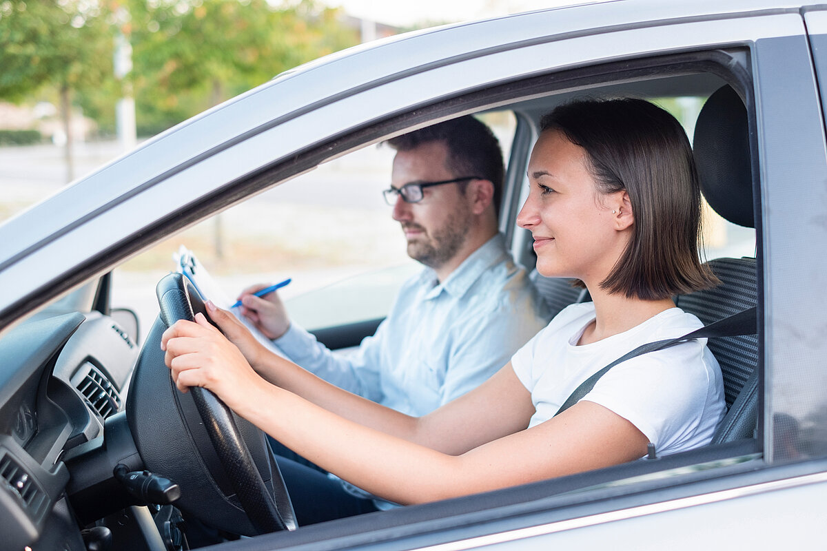 Fahrlehrer und Fahrschülerin im Auto