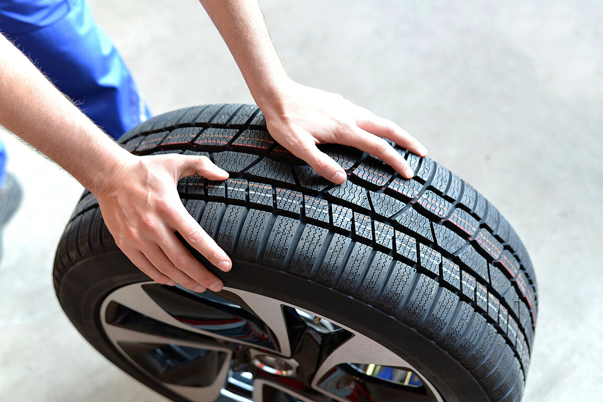 Mechaniker rollt einen Sommerreifen