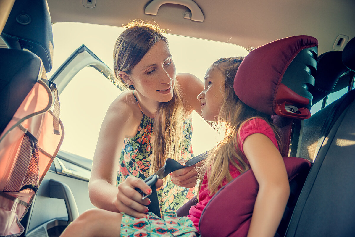Eine Frau schnallt ihre Kinder im Auto an