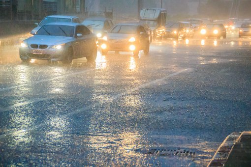 Autos fahren durch Platzregen und Gewitter auf einer Straße