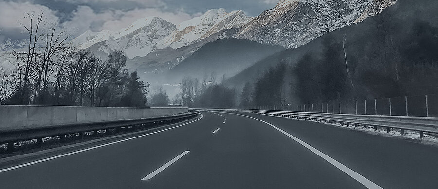 Eine Fahrbahn die an einem Schnee bedeckten Berg vorbei führt