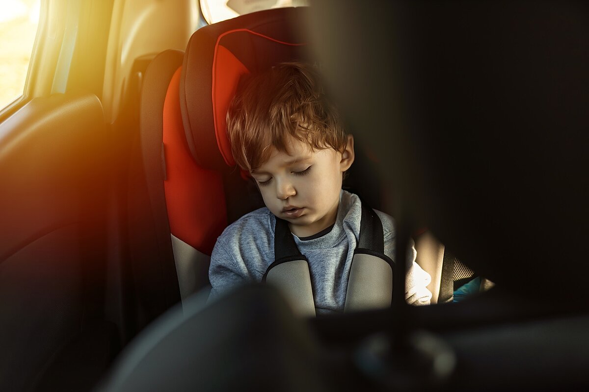 Kleinkind schläft allein im Kindersitz bei Sonneneinstrahlung im Auto – Warnung vor Hitzestau und lebensgefährlicher Überhitzung bei Kindern.
