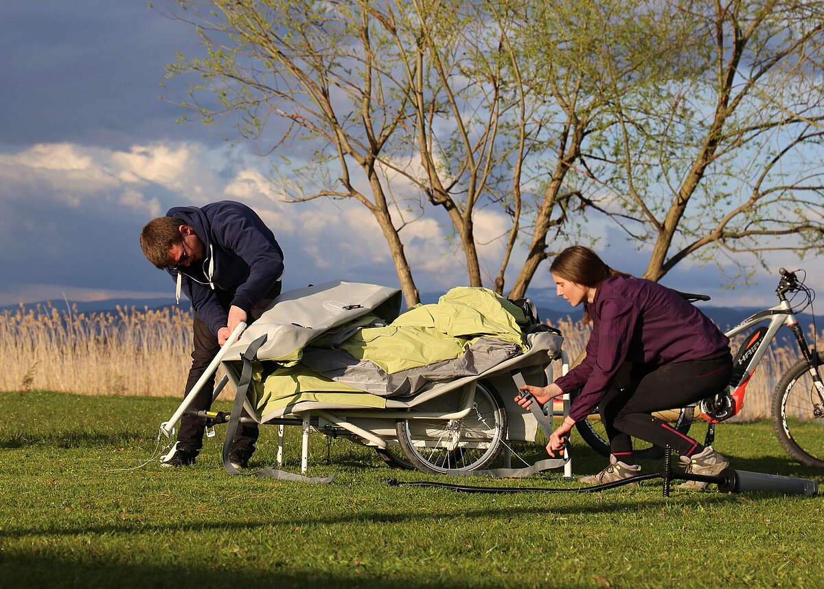 Zwei Personen bauen einen Microcaravan für das Fahrrad auf