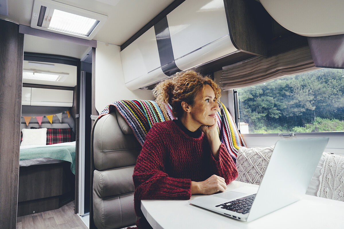 Eine Frau sitzt an Ihrem Laptop in einem Wohnmobil