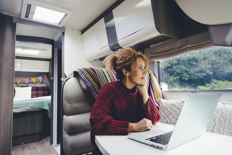 Eine Frau sitzt an Ihrem Laptop in einem Wohnmobil