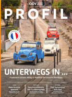 Drei klassische Citroën-Autos, zwei blaue und ein rotes, fahren eine gepflasterte Straße in einem malerischen französischen Dorf mit Steintreppen, alten Gebäuden und Blumen entlang des Weges hinauf. Textüberlagerungen behandeln Reise- und Autothemen.