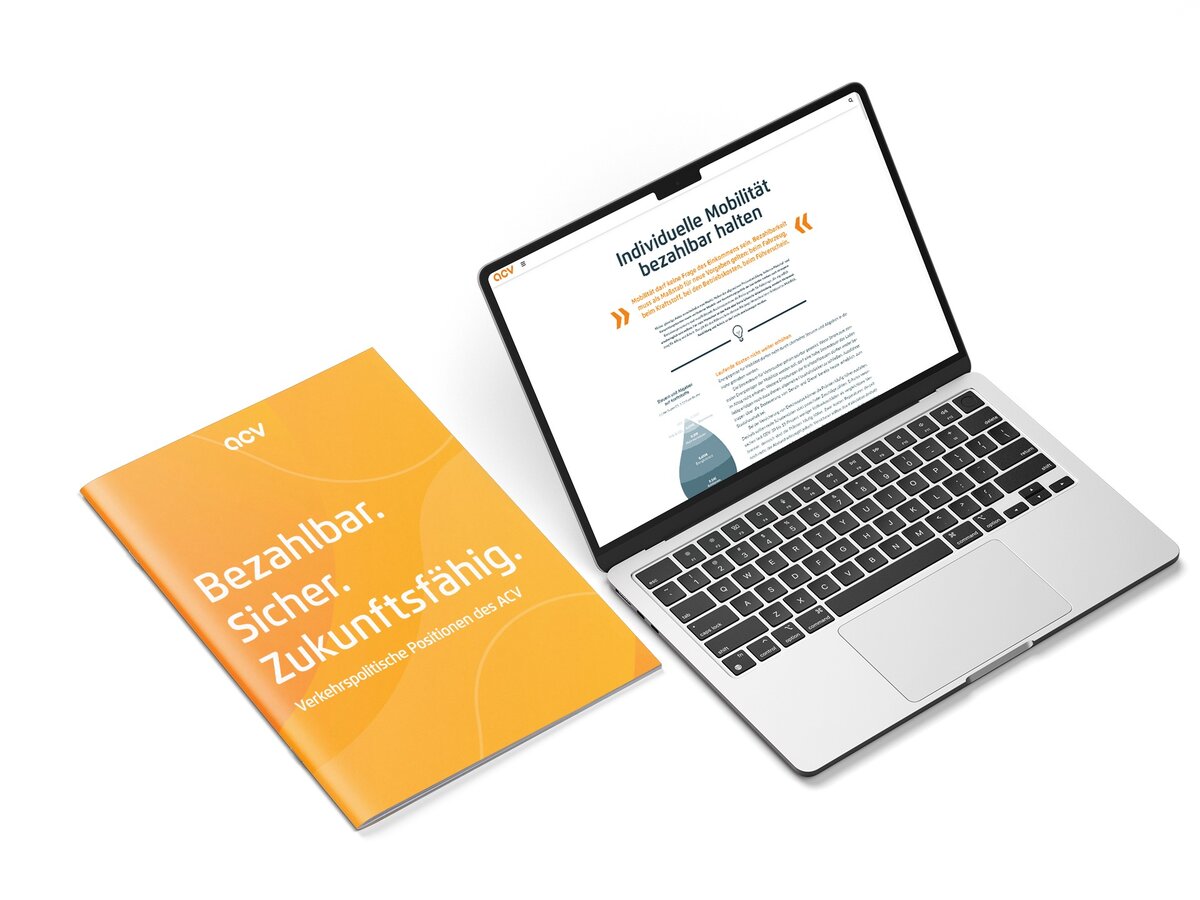 Neben einem silbernen Laptop, auf dessen Bildschirm eine Website über erschwingliche, nachhaltige Mobilitätslösungen zu sehen ist, liegt eine gelbe Broschüre mit der Aufschrift Bezahlbar. Sicher. Zukunftsfähig. – beides vor weißem Hintergrund.