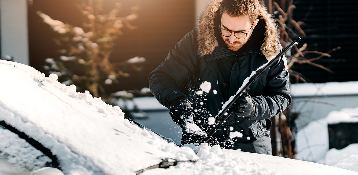 Mann befreit sein Auto von Schnee