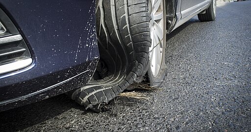 Zerstörter Pkw Reifen nach Reifenplatzer auf der Autobahn.