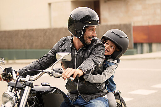 Mann fährt Motorrad mit Kind
