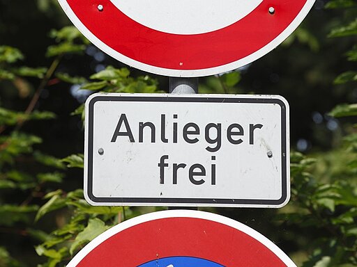 Verkehrszeichen 'Durchfahrt verboten' (rotes rundes Schild mit weißer Mitte) mit Zusatzschild 'Anlieger frei' (weißes rechteckiges Schild mit schwarzer Schrift). Bedeutet: Allgemeines Fahrverbot, aber Anlieger mit berechtigtem Anliegen dürfen passieren.
