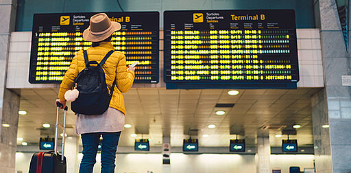 Frau steht mit einem Koffer am Flughafen