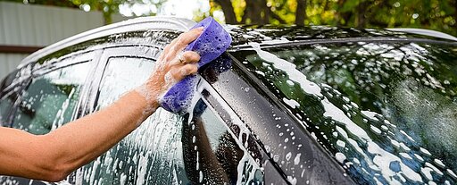 Eine Person wäscht ein schwarzes Auto
