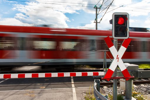 Zug fährt an Bahnübergang vorbei