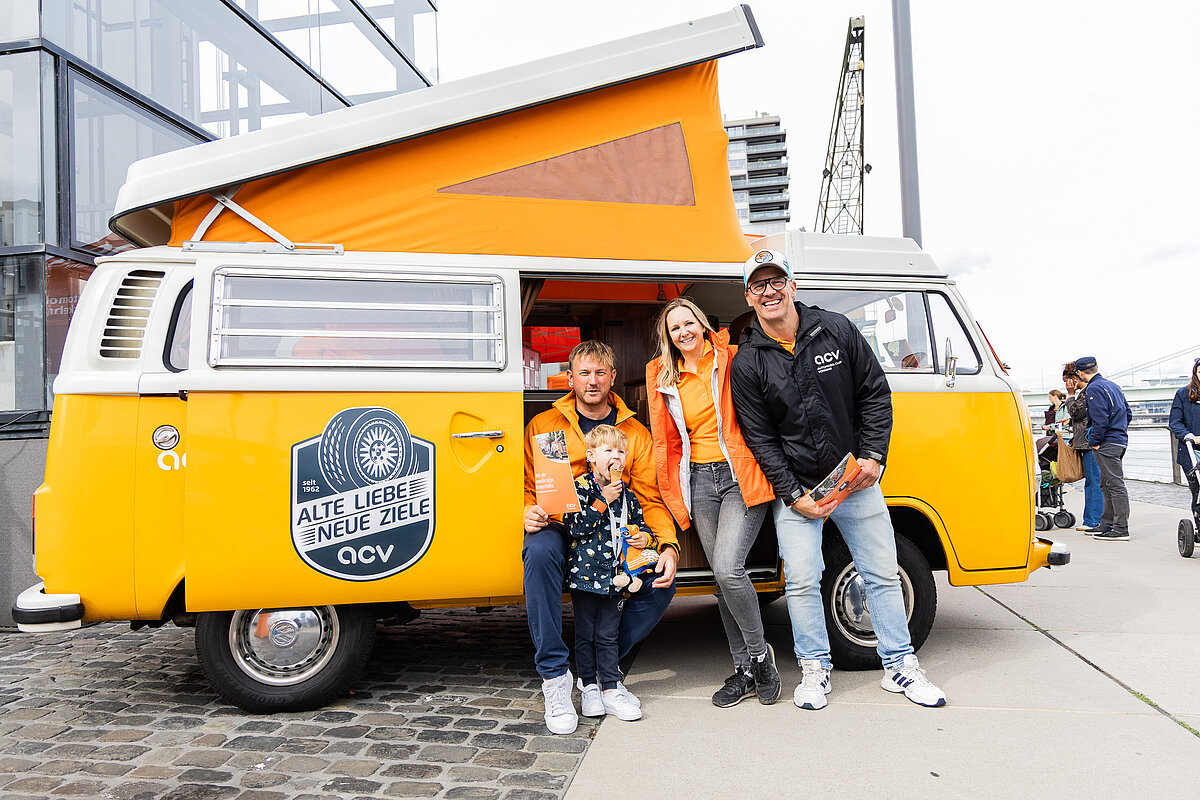 ein team des acv stehen mit einem kind vor dem oldtimer vw bulli des acv