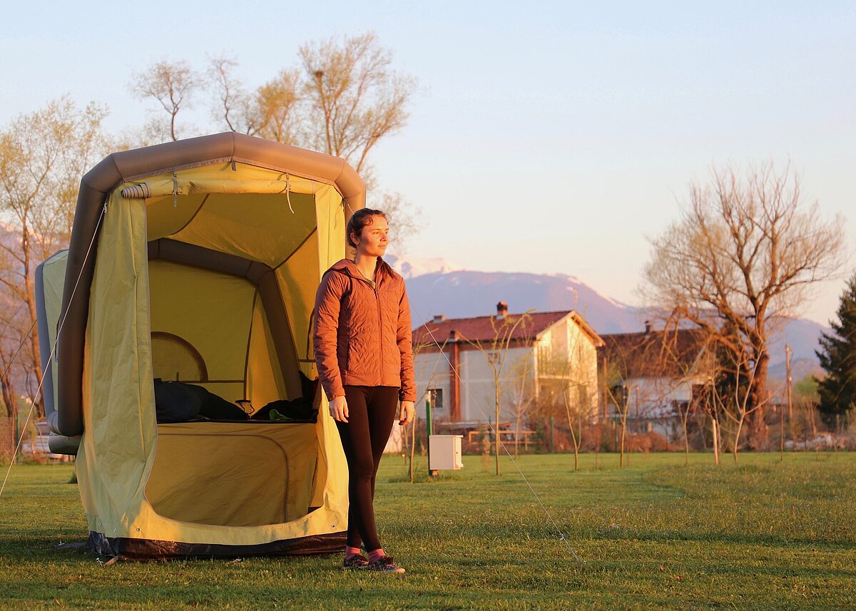 Eine Person steht vor einem Microcaravan auf einer Wiese