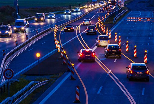 Autos fahren an einer Baustelle auf einer Autobahn im Dunkeln entlang