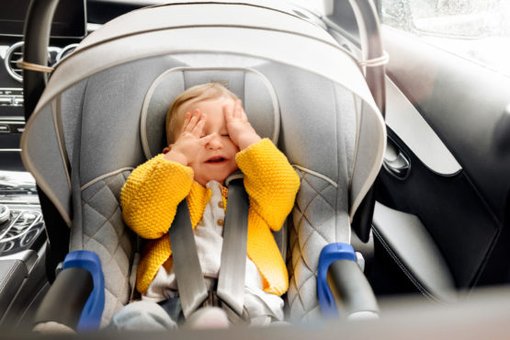 Baby sitzt in einer Babysitzschale im Auto
