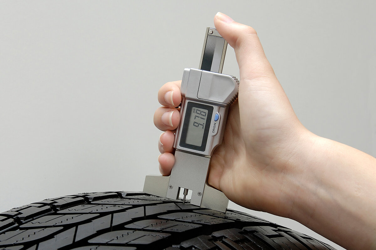 Mechaniker misst die Profiltiefe an einem Reifen