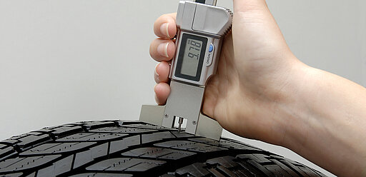 Mechaniker misst die Profiltiefe an einem Reifen