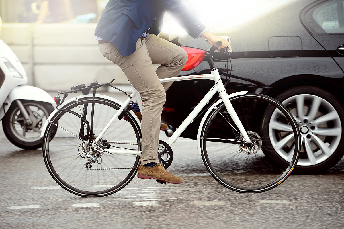 Mann fährt mit einem Fahrrad an Autos vorbei