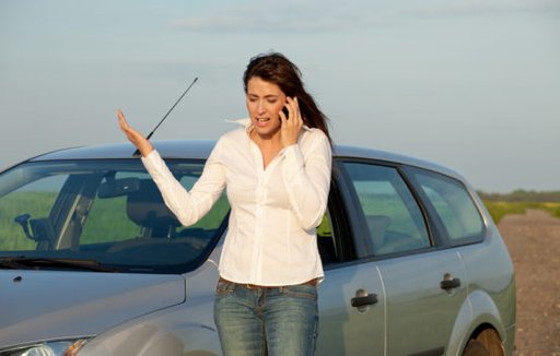 Eine Frau telefoniert aufgeregt neben ihrem Auto
