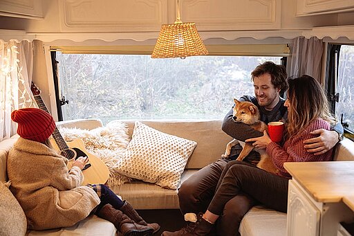 Eine Familie sitzt mit ihrem Hund in einem Camper im Winter