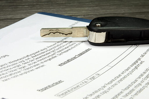 Auf einem Kaufvertrag liegt ein Autoschlüssel