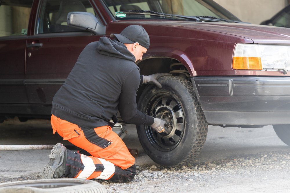 Abschlepphelfer wechselt an einem Auto den Reifen