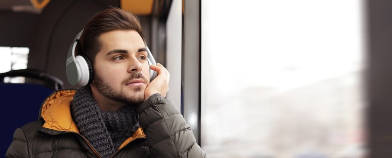 Ein Mann hört im Bus mit Kopfhörern den ACV Podcast