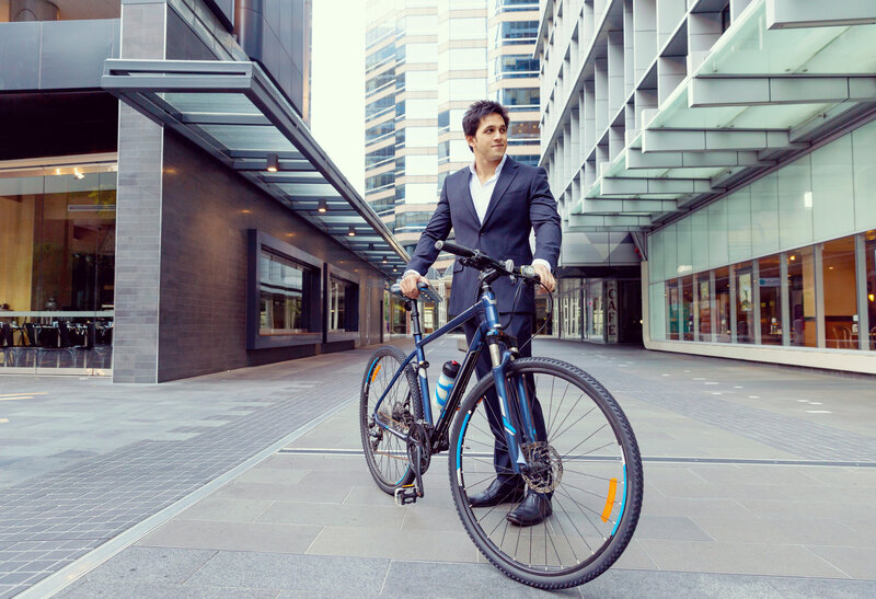 Frau fährt mit einem Fahrrad an Bürogebäuden vorbei