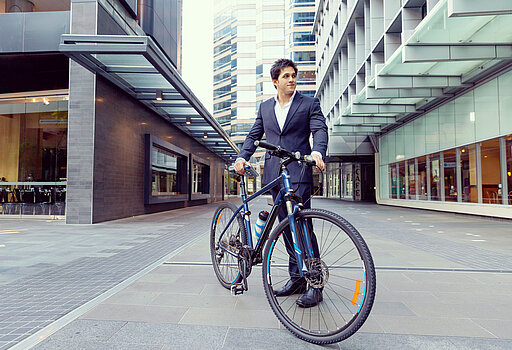 Frau fährt mit einem Fahrrad an Bürogebäuden vorbei