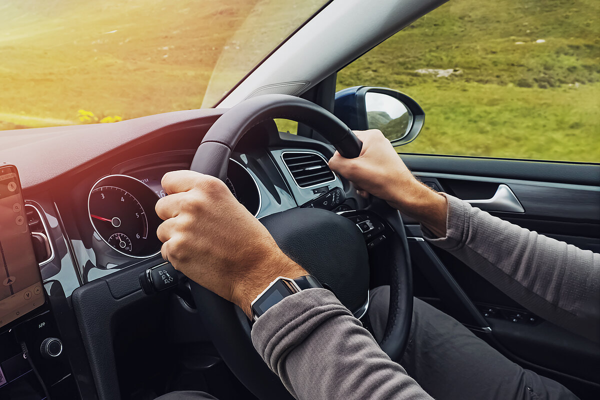 Eine Person hält mit beiden Händen das Lenkrad im Auto