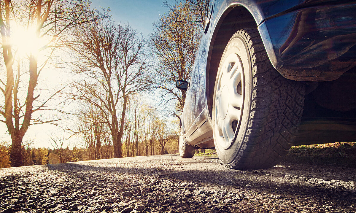 blaues Auto fährt an Bäumen vorbei