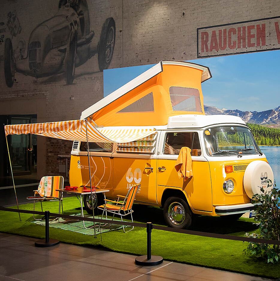 Alter gelber VW Bulli steht in einer Messehalle