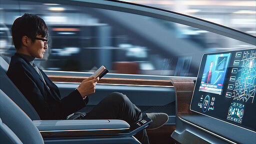 Mann sitzt in einem Auto, das autonom fährt