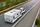 Ein weißes Auto fährt mit einem Gespann über die Autobahn