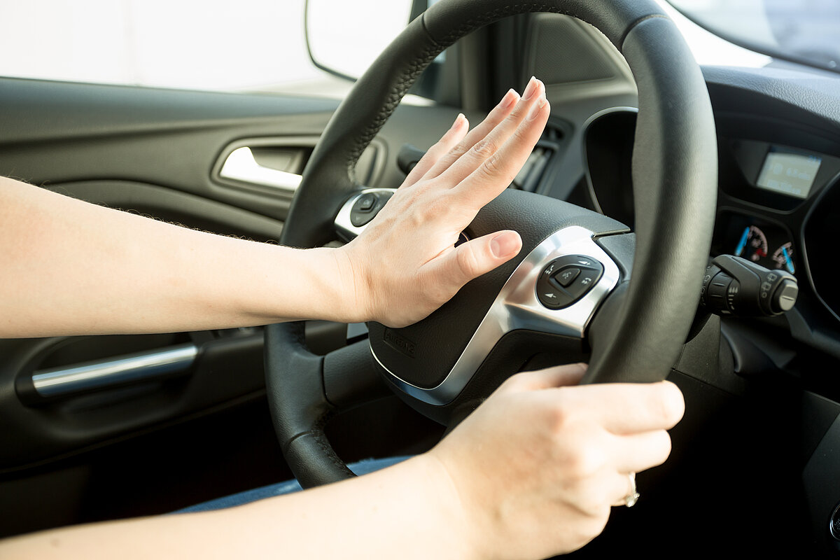 Person betätigt die Hupe im Auto