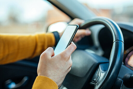 Frau hat ein Handy am Steuer