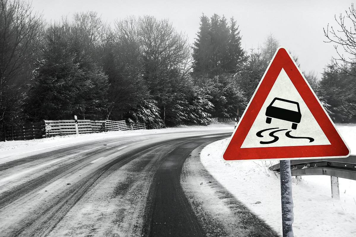 Verkehrsschild warnt vor Kurve vor Rutschgefahr