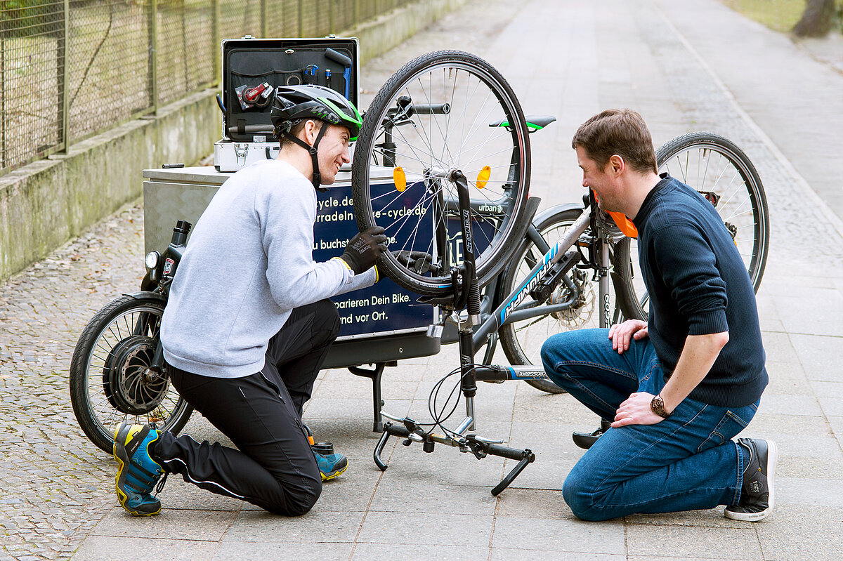 Zwei Männer reparieren ein Fahrrad