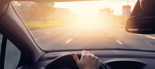 Eine Person fährt bei tief stehender Sonne auf einer leeren Straße.