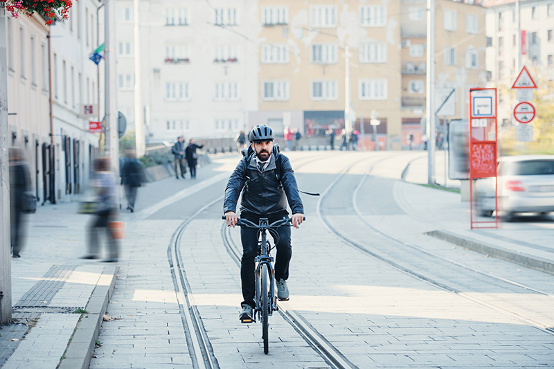 Person fährt mit einem Pedelec an Bahnschienen vorbei